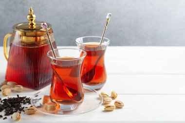Beyaz ahşap masada lezzetli Türk çayı, şeker ve şam fıstığı. Metin için boşluk