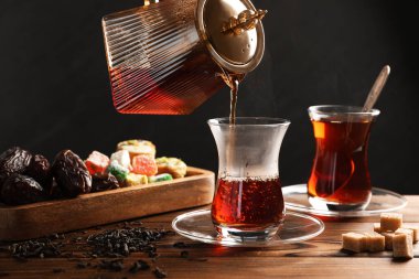 Tahta masada cam fincana Türk çayı dökülüyor, yakın plan.