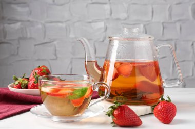 Çilekli aromalı meyve çayı ve beyaz mermer masada nane şekeri, yakın plan.