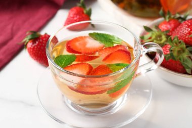 Çilekli aromalı meyve çayı ve beyaz mermer masada nane şekeri, yakın plan.