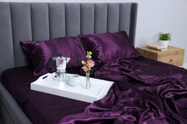 Mor ipek çarşaflar, içinde kahve ve çiçekler olan tepsiler.