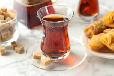 Lezzetli Türk çayı, beyaz mermer masada şekerlerle servis edilir, yakın plan.