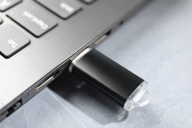 Gri desenli masadaki dizüstü bilgisayara bağlı flaş bellek, yakın plan.