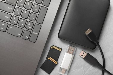 Flaş bellek, SD hafıza kartları, harici sabit disk ve dizüstü bilgisayar gri desenli tabloda düz konum