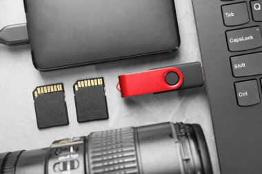 Dizüstü bilgisayara, SD hafıza kartlarına, harici sabit diske ve gri dokuma tablosundaki kamera lensine bağlı flaş bellek, düz konum