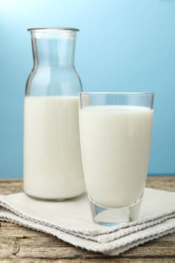 Açık mavi arka planda, ahşap masada taze süt, yakın plan.