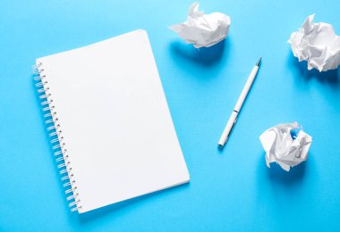 Boş bir defter aç, buruşmuş kağıt ve kalem açık mavi arkaplanda, düz uzan