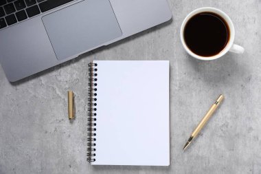 Kalem, açık defter, kahve ve dizüstü bilgisayar gri masada, düz yatıyordu.