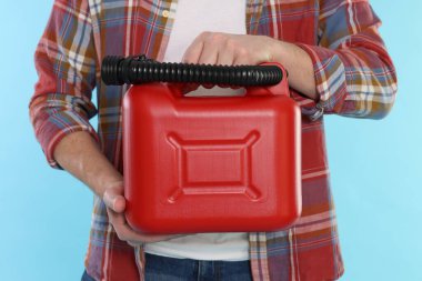 Açık mavi arka planda plastik kutu tutan adam, yakın plan.