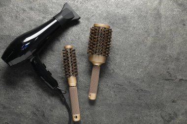 Gri desenli arka planda saç kurutma makinesi ve fırçalar. Metin için boşluk