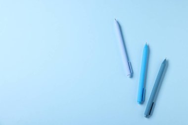 Açık mavi arka planda şık kalemler, düz yatış. Metin için boşluk