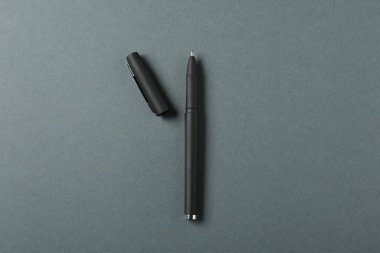 Gri arka planda şık bir kalem ve kapak, üst görünüm