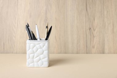 Tahta arka planda, bej masadaki tükenmez kalemler. Metin için boşluk