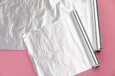 Pembe arka planda alüminyum folyo ruloları.