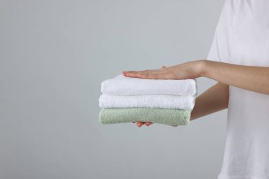 Arka planda temiz havlu yığını tutan kadın, yakın plan. Metin için boşluk