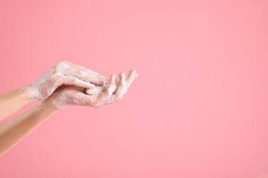 Açık pembe arka planda ellerini sabunla yıkayan kadın, yakın plan. Metin için boşluk