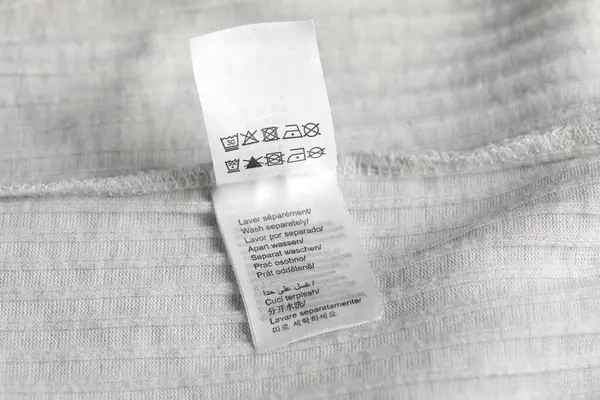 Arka plan olarak hafif giysi üzerinde özen sembolleri olan giyim etiketi, yakın plan