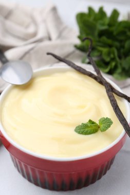 Lezzetli vanilyalı puding, nane ve kapsüller beyaz fayanslı masada, yakın plan.