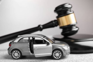 Motorlu taşıt kazası yasası. Gri arkaplanda Gavel ve araba modeli