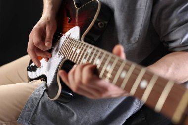 Siyah arka planda gitar çalan adam, ele odaklan.