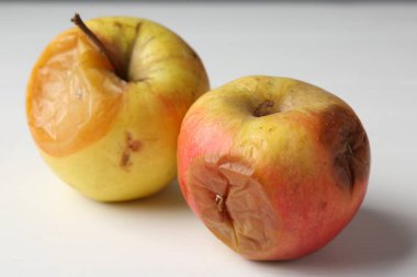 Beyaz ahşap masada çürük elmalar, yakın plan.