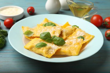 Açık mavi ahşap masada servis edilen peynirli ve fesleğenli lezzetli ravioli.