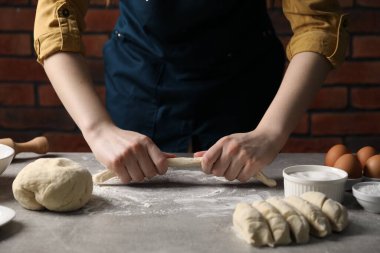 Açık gri masada simit yapan kadın, yakın plan.
