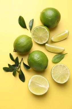 Sarı arka planda taze limonlar, düz uzanmış.