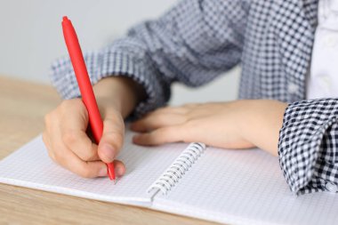 Küçük çocuk ahşap masada ödev yapıyor. Kapalı bir masa.