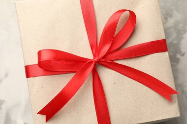 Kraft kağıdına sarılı hediye, gri desenli arka plan, yakın plan.