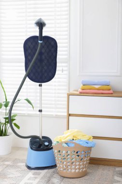 Kapalı alanda temiz çamaşırları olan modern, dik bir buharlı sepet.