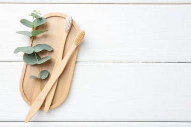 Bambu diş fırçaları ve okaliptüs dalları beyaz ahşap masa, üst manzara. Metin için boşluk