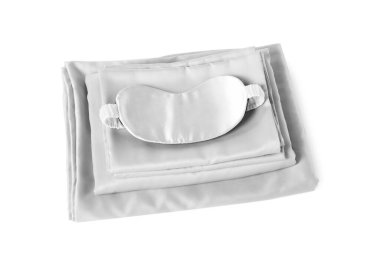 Beyaz arka planda ipek çarşaflar ve uyku maskesi.