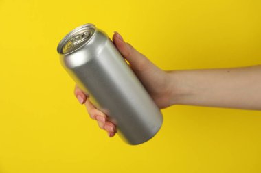 Sarı arka planda teneke kutusu olan kadın, yakın plan.