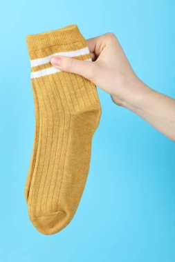 Açık mavi arka planda bir çift çorap giyen kadın, yakın plan.
