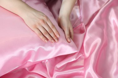 Yastıklı ve ipek çarşaflı bir kadın.
