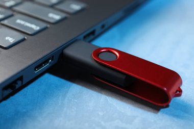 Mavi desenli masadaki dizüstü bilgisayara bağlı Usb flash diski, yakın plan