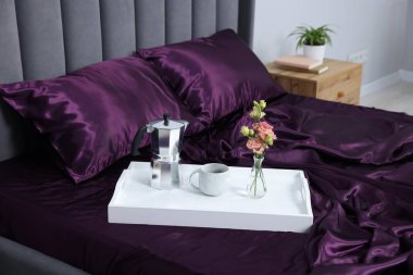 Mor ipek çarşaflar, içinde kahve ve çiçekler olan tepsiler.