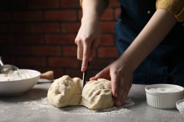 Açık gri masada hamur kesen kadın, yakın plan.