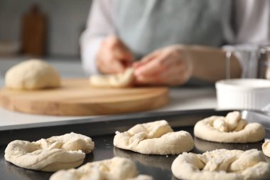 Mutfaktaki masada simit şekillendiren kadın, seçici odaklanma.