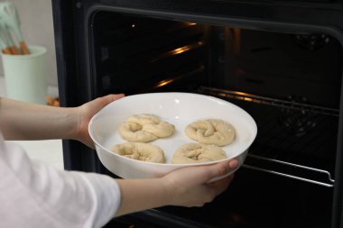 Pişmemiş krakerlerle fırına yemek koyan kadın, yakın plan.