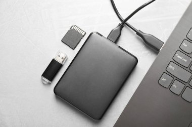 Gri desenli tablo üzerinde dizüstü bilgisayara, hafıza kartına ve flash diske bağlı harici sabit disk, düz konum