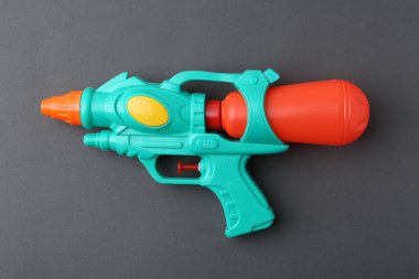 Gri arkaplanda parlak plastik su tabancası, üst görünüm