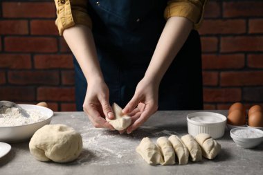 Açık gri masada hamur yoğuran kadın, yakın plan.