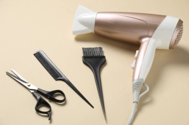 Bej arkaplanda tarak, makas, fırça ve kurutucu, üst görünümde