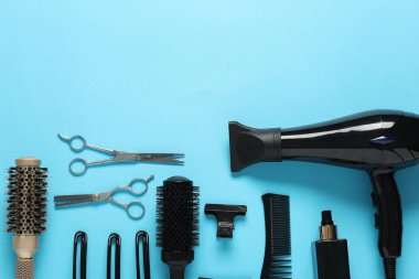 Açık mavi arka planda farklı saç şekillendirme araçları, düz yatış. Metin için boşluk
