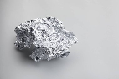 Açık gri arka planda buruşmuş alüminyum folyo parçası, yakın plan. Metin için boşluk