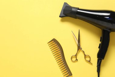 Sarı arka planda farklı saç şekillendirme araçları, düz yatış. Metin için boşluk