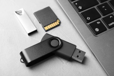 Flaş bellek, hafıza kartı ve dizüstü bilgisayar açık gri masada, yakın plan.