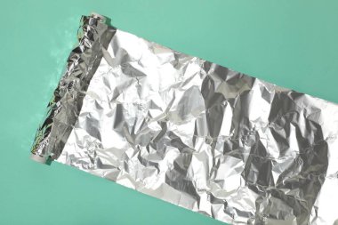 Turkuaz arka planda alüminyum folyo rulosu, üst görünüm